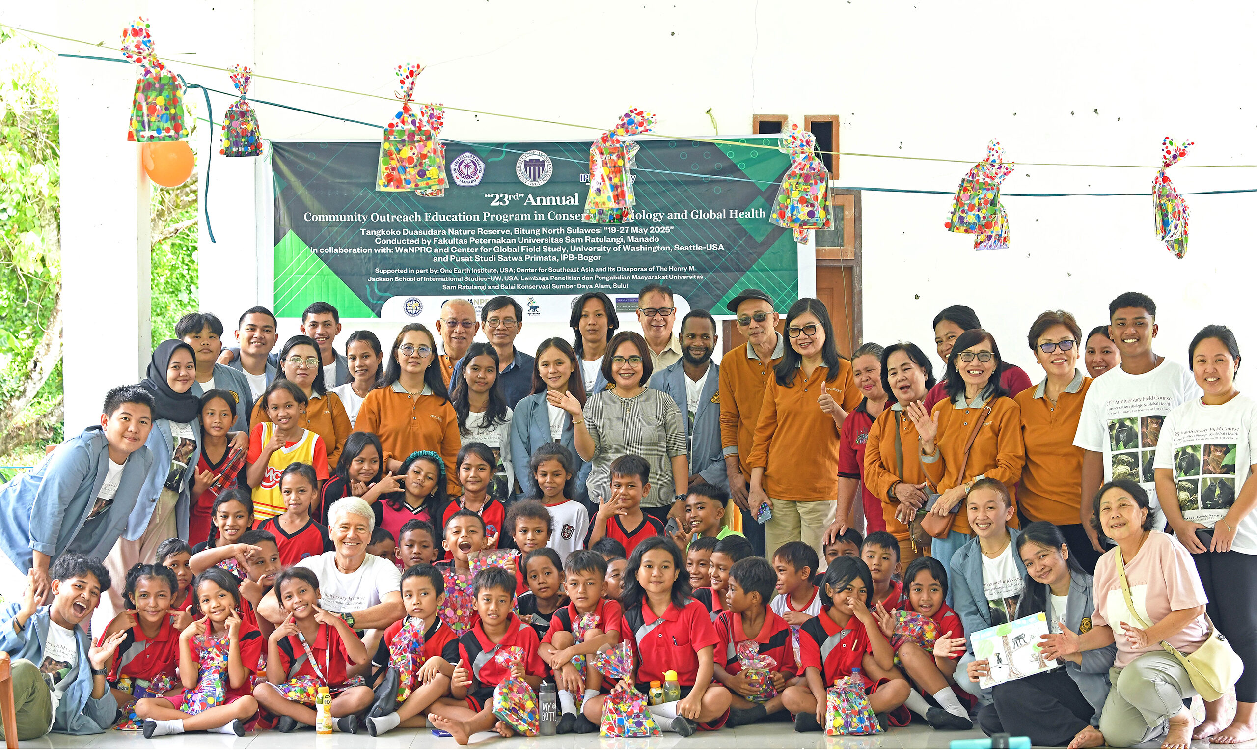 group photo of outreach activity participants, teachers and elementary school children wearing red uniforms in Indonesia